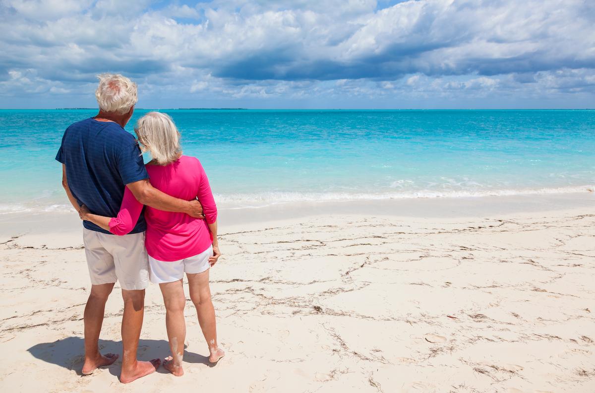 Older Couple standing on the beach looking out at the ocean